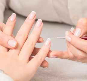 Hand young woman receiving french manicure by beautician nail salon